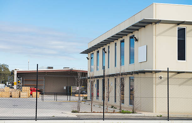 Modern office building with industrial warehouse and workshop  on the rear plan